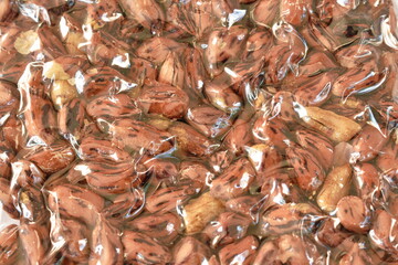 close up of baked salty tiger stripe peel peanut in clear plastic packaging on white background