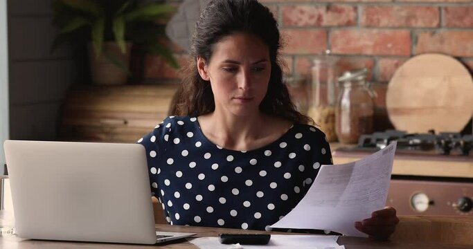 Young frustrated woman sit with laptop in kitchen at home feels worried checking bills due high taxes, unpaid invoice need to pay. Concept of financial problem, lack of money, overdue and debt concept