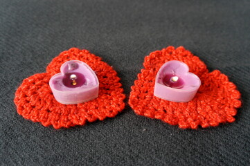 Valentine's Day . Lighted candles in the form of a heart on a background of knitted red hearts .