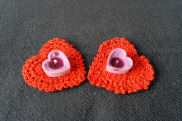 Valentine's Day . Lighted candles in the form of a heart on a background of knitted red hearts .