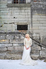 Beautiful bride near old castle on winter wedding day