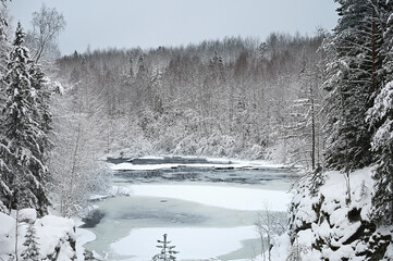 Landscape with a frozen river in the middle of a snow covered forest