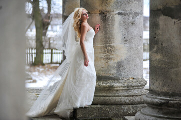 Obraz premium Beautiful bride near old castle on winter wedding day