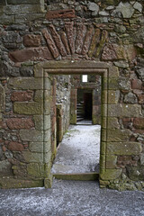 Details of ruined Balvaird Castle in Scotland, showing doorway looking through to passageway and spiral stone staircase. Snow on ground.