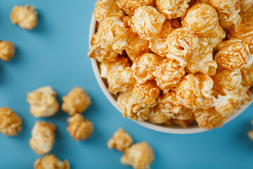 Caramel of the popcon in a white cup with a scissor on a blue background.