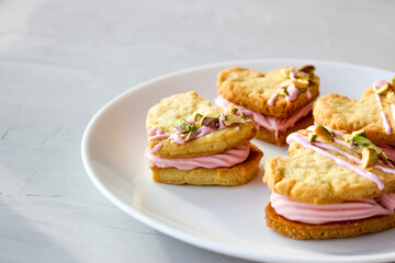 Holiday cookies in the shape of a heart, with cottage cheese cream and pistachios