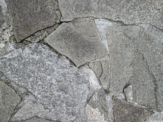 Cracked stone surface. The hardened coating of an old house.