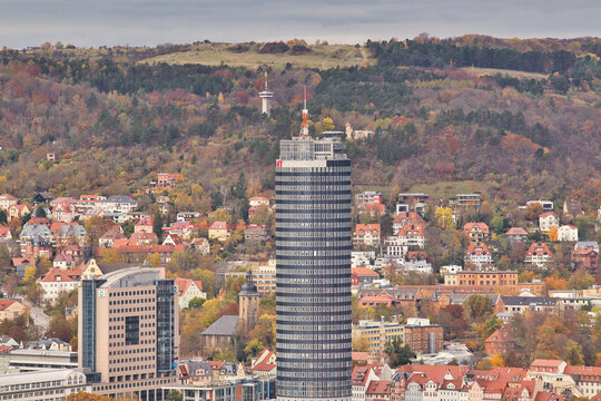 Detailansicht des JenTower Wolkenkratzers &uuml;ber den D&auml;chern der Stadt vor herbstlich bewaldeten H&auml;ngen im Saaletal, Jena, Stadt Jena, Th&uuml;ringen, Deutschland