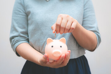 business woman hold piggy bank and putting coin with concrete wall for financial and saving money...