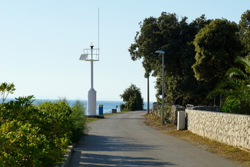 Promenade by the sea with a small white lighthouse in a coastal village