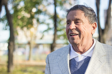 Portrait of happy senior man smiling, in the public park, outdoors