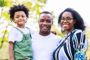 Portrait of African American family. Happy African American parent (Father, mother) and son are smiling together while standing in the park in the daytime in summer. Happy family concept.