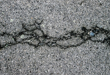 A large crack in the asphalt. Broken stone texture for overlays and posters.