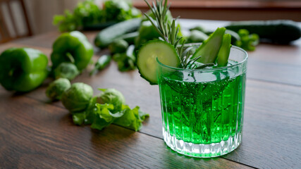 Green lemonade with cucumber and rosemary on wooden table.