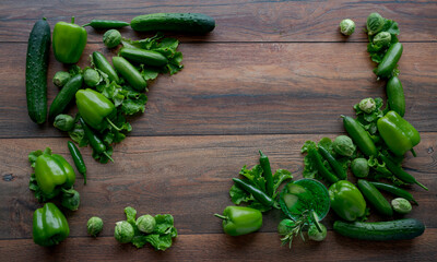 Food background. Bell green peppers, cucumbers, hot green chili peppers, brussels sprouts, green salad on wooden table.