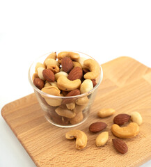 Nuts in circle shaped glass bowls on wooden Butcher isolated with copy space on white background. Various nuts (almonds, macadamia, cashew, peanuts). Mix nut  healthy ingredients food.