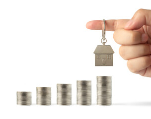 Key ring miniature house in hand on growing stack of coins money isolated on White background using as property real estate and financial savings plans for housing, financial concept.