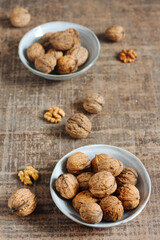 Walnuts in a blue grey dish on a rustic brown background, shot overhead. Food photography style. Flat lay with copy space.