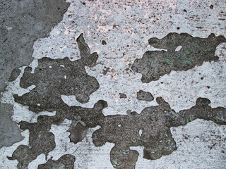 Decaying surface of an old concrete wall. Dents and crumbling surfaces. The texture of potholes and scuffs.