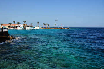 Fototapeta na wymiar Turquoise sea, white yachts and beach in the background