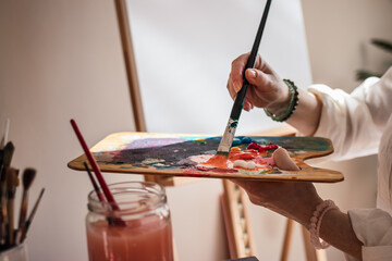 Creative abstract painting. Woman mixing acrylic colors at palette and working on paintings. Artist...