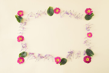 Fototapeta na wymiar Frame made with spring flowers on beige background.Nature and Mother's day concept.Minimal flat lay.