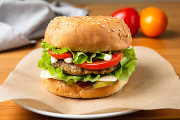 Burger with meat patty melted cheese with lettuce tomato cucumber with sauce is suitable for quick hunger quenching