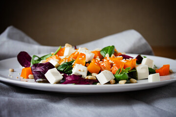 A nutritious salad for dinner lunch with pumpkin pine nuts cheese and spinach drizzled with butter and lemon juice