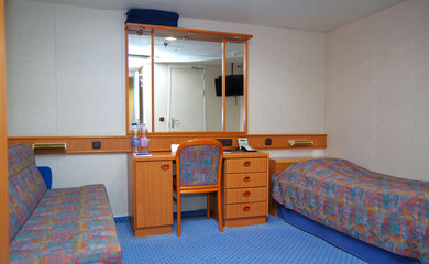 Cozy but dated cabin or stateroom on classic cruiseship or cruise ship liner with desk, bed, chair...