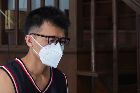 Asian Man Wear Basketball Jersey With Hygienic Mask And Sitting In House