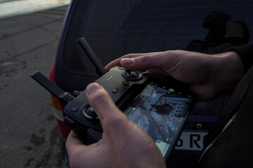 man controls the drone using the remote control and the phone