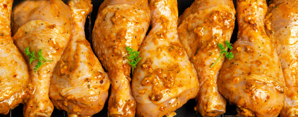 Raw chicken drumsticks marinated red with turmeric, garlic, mustard and parsley. Lined with chicken on a wire rack, ready to bake. B-B-Q. Home kitchen. Top view.