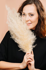 Charming middle aged woman smiling at camera from behind fluffy cereal brunch. She has subtle cat eye makeup, she wears black shirt