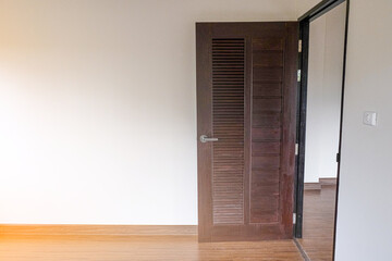 open brown door with white wall in new house. wooden laminate floor in living room.