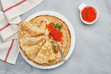 Crepes, thin pancakes, Russian pancakes with red caviar on gray plate. Marble background. Copy space. Top view.