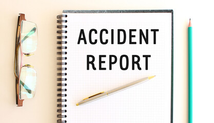 Notepad with text ACCIDENT REPORT on a white background, near glasses and pencil.