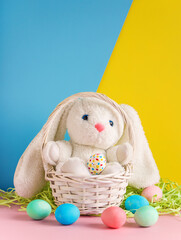 happy easter background cute bunny toy and decorated eggs in wicker basket on duot one blue yellow background vertical