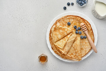 Crepes, thin pancakes or blini with berries in white plate. Top view. Pancake week. Shrovetide. Space for text.