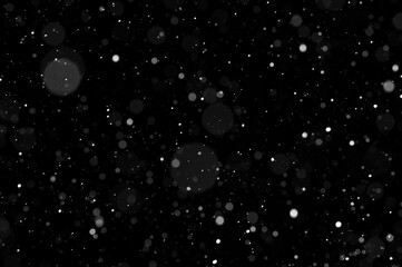 Bokeh of white snow on a black background. Snowfall - design element.
