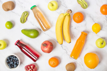 set of fruit juice bottles with fresh fruits on gray table