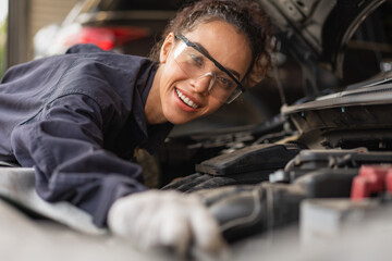 Female mechanic smiling and working repair maintenance a car in the auto service garage