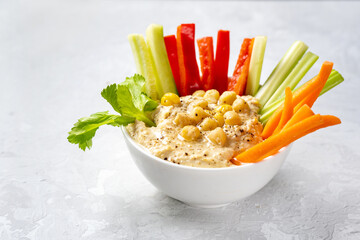 Close up of a plate with hummus dip and vegetables sticks on white background. Healthy enriched...