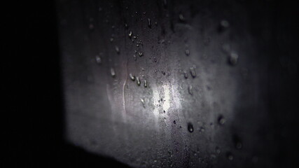 Misted car window with water drops at night