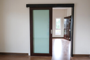 connection room glass open brown door with white wall in new house. wooden laminate floor in living room.