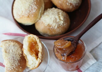 Round buns with filling in a natural wicker plate for tea and apple jam on a gray background. Ready to eat. Home cooking concept.
