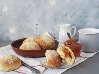 Round buns with a filling in a natural wicker plate for tea on a gray background. Ready to eat. Home cooking concept.Bread and rolls.