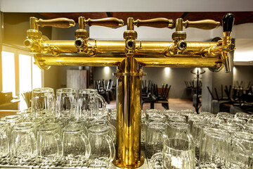 Close up of a beer faucet or tap with huge arrenge of an empty glasses in the bar or pub, restaurant concept