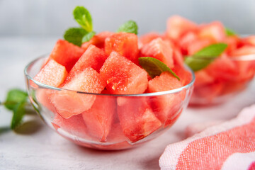 Crop shot of glass bowl with juicy and sweet watermelon cubes decorated with mint. Summer refreshing and vitaminized raw vegan food
