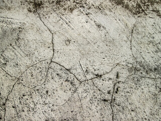 Texture of cracks on a grainy gray wall. Concrete surface with old cured cement.