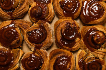 Homemade cinnamon buns with spices and caramel on parchment paper.